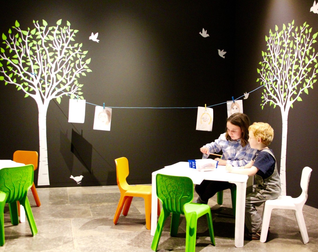 Zwei Kinder sitzen an einem kleinen weißen Tisch in der Ausstellung des MAKK.