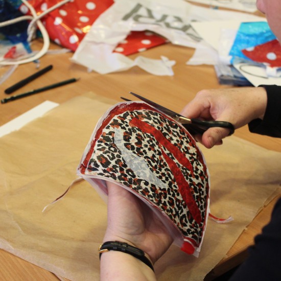 A woman cuts a piece of fabric with scissors.