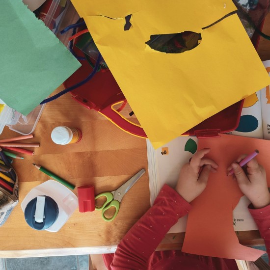 Children sitting around a table, crafting with colorful paper.