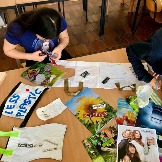 Kinder sitzen um einen Tisch und basteln gemeinsam kleine Flaggen.