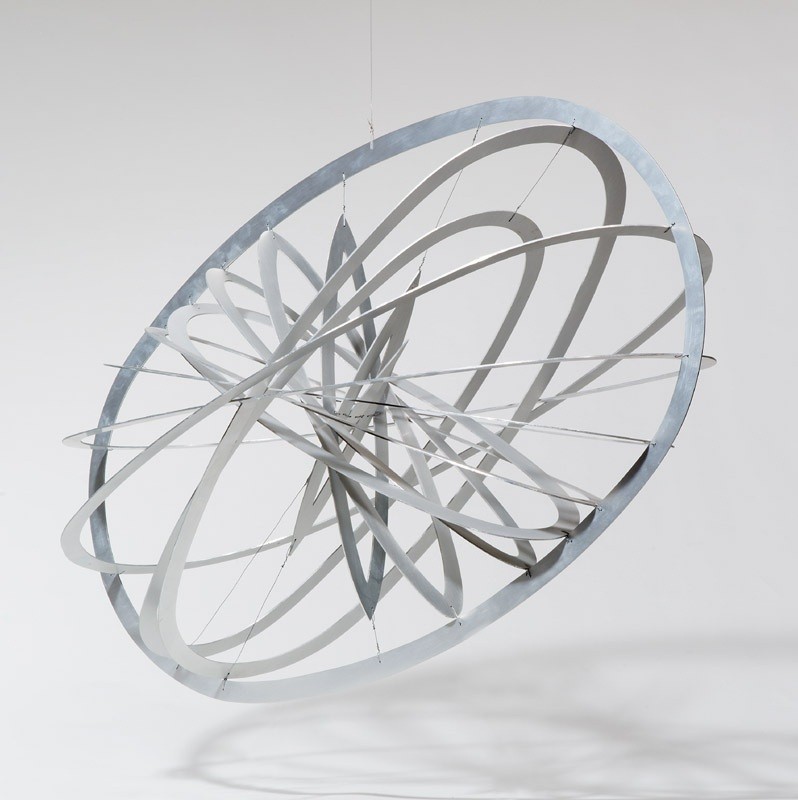 Hanging object made of concentric ovals of aluminum strip in three-dimensional rotation.