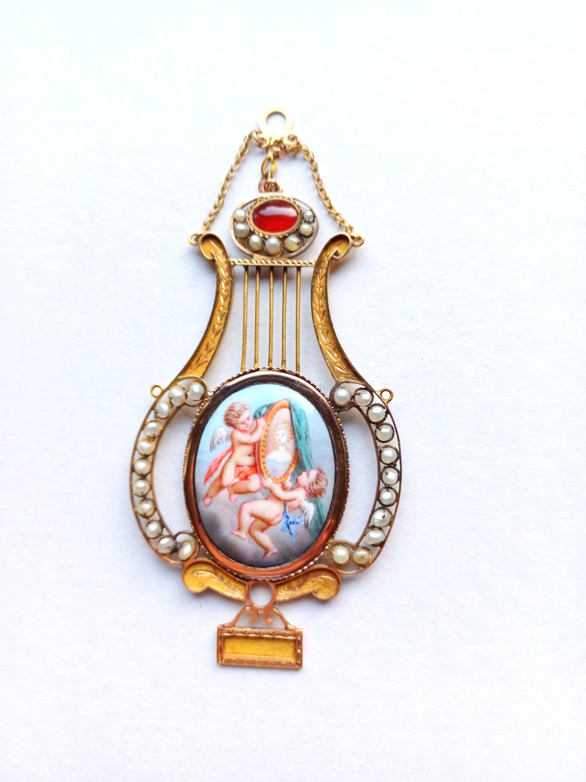 Goldener Anhänger mit Perlen in Form einer Lyra. Mittig ein Medaillon mit Putti.