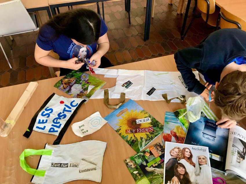 Kinder sitzen um einen Tisch und basteln gemeinsam kleine Flaggen.