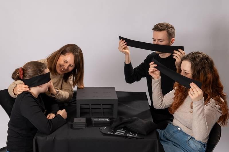 Vier Personen sitzen an einem Tisch und spielen.