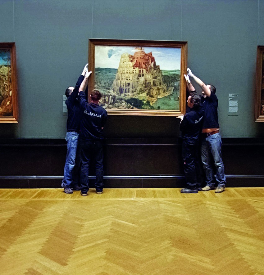 Männer hängen in einem Museum ein Bild auf.